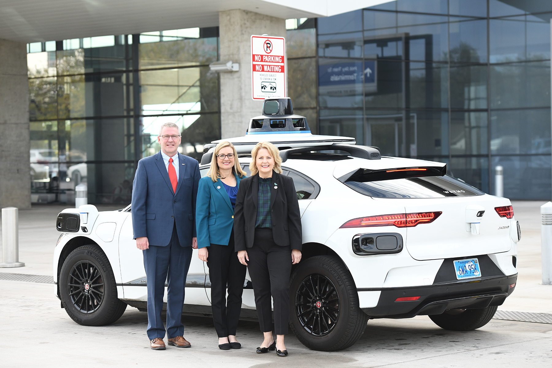 Three VIPs standing in front of a Waymo Autonomous car