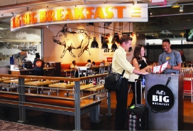 Hostess at Big Breakfast showing the menu to two customers.