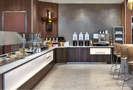 A buffet with food and coffee or drink bar with counter to sit at.